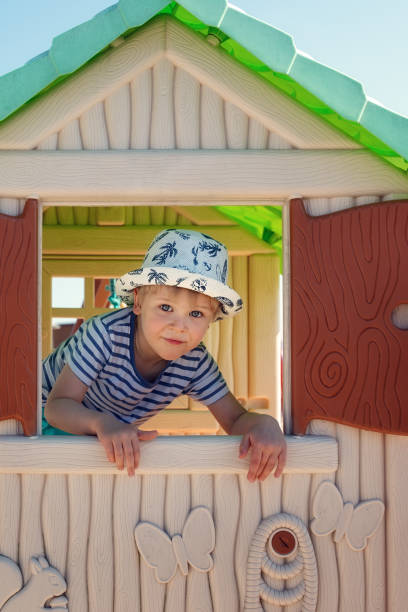istock A cheerful little boy in a hat, inside a toy little house. 1392389761