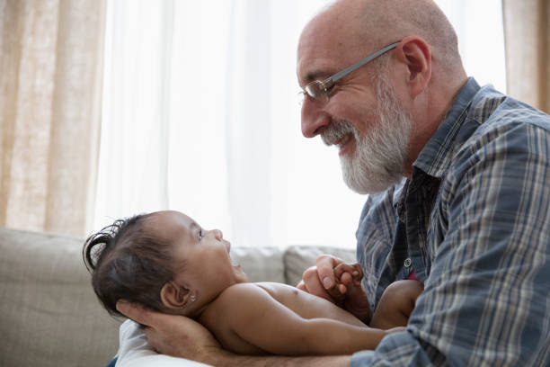Grandparents Holding Sleeping Newborn Baby Granddaughter Smiling