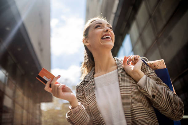 молодая женщина держит сумки с покупками в городе с кредитной картой - credit card paying boutique young women стоковые фото и изображения