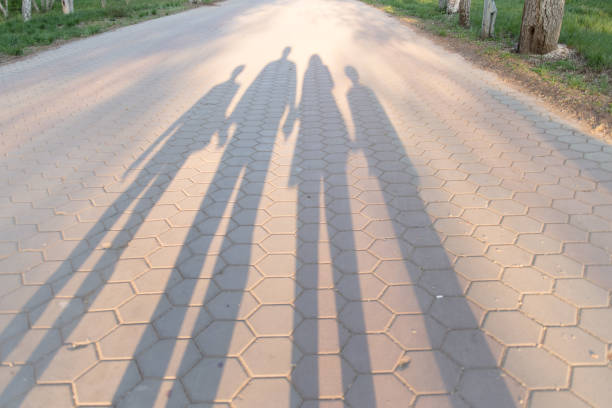 Family relationship concept silhouettes of adults and children holding hands shadow on the road