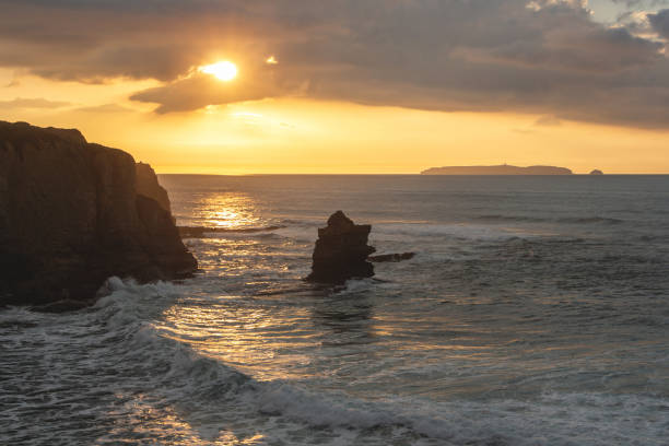 istock Orange sunset on the ocean with sheer cliffs and foamy waves 1392392070