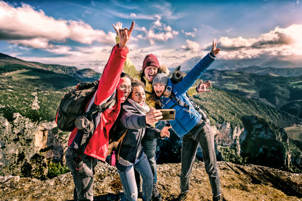amis heureux randonneurs avec sacs à dos prenant selfie portrait au sommet de la montagne - souriant heureux touristes grimpeurs profitant des vacances d’été en haute altitude - liberté, succès concept sportif - exploration group of people hiking climbing photos et images de collection