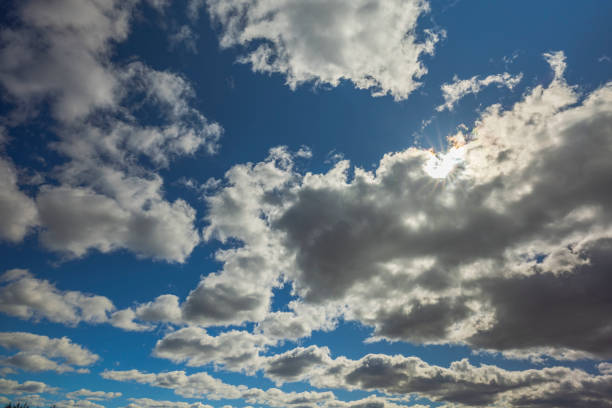 Beautiful view of sun's rays breaking through white clouds against  bare sky. Sweden.