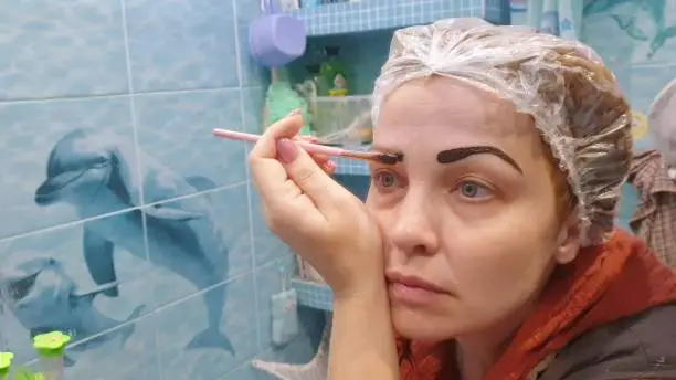 self-tinting eyebrows at home, woman brush dye eyebrows