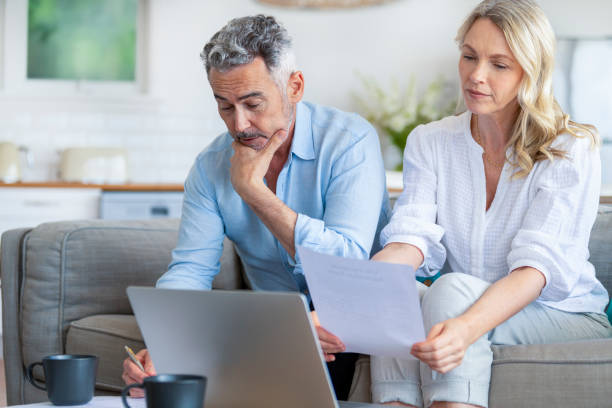 istock Mature couple using a laptop computer and doing paperwork on the sofa 1392406545