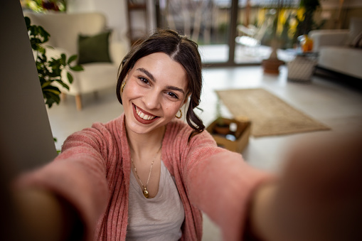 Beautiful smile young woman taking selfie by mobile phone from home