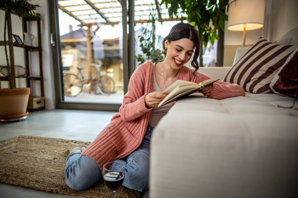istock Happy young woman reading a book at home 1392408043