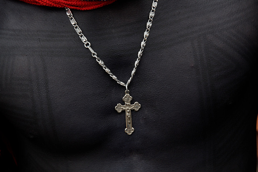 Silver christian cross and necklace worn by an indigenous man with skin painted black. Xingu River. Jogos Indígenas, 2010.