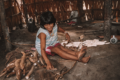 Indigenous woman from Arawete tribe peeling cassava on the floor. Índia Amazônica Brasileira. Xingu River, Altamira, Brazilian Amazon 2007.