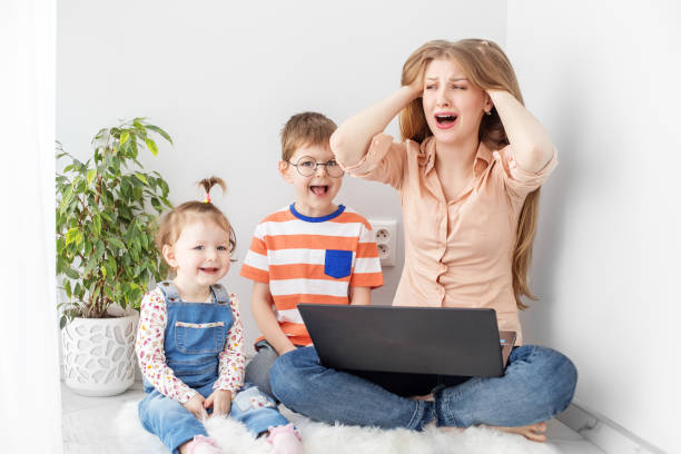 istock Busy woman trying to work while babysitting two kids. Great stress. 1392413231