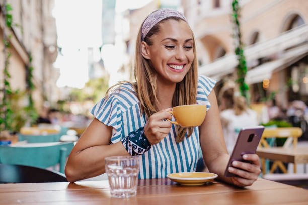 istock Beautiful woman is using mobile phone outdoors in restaurant 1392415030
