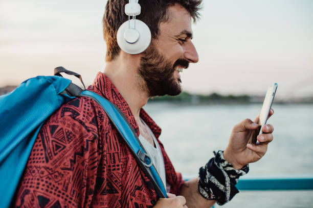 istock Handsome man is using wireless headphones and mobile phone on the street 1392415066