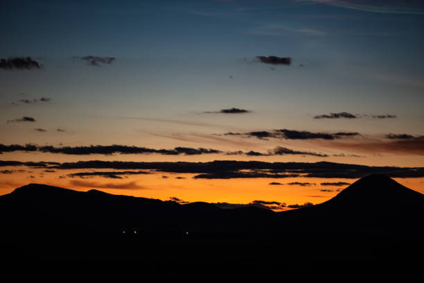 Mountains in Arizona silhouetted against a fiery orange sunset.