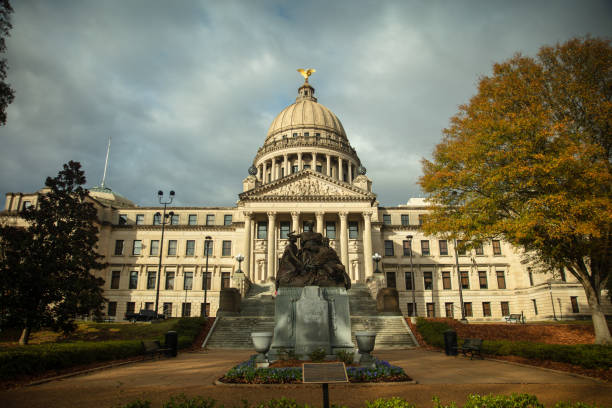 Frontal view of the Mississippi State Capitol Building and Women of the Confederacy Monument in Jackson on an overcast day in Fall.