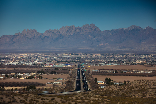 Interstate 10 running through Las Cruses, New Mexico on a clear day in springtime, with the Organ Mountains looming in the distance.