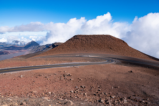 Roads curve into an intersection in the barren landscape of a volcanic crater beneath mountain peaks