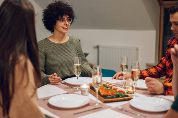 istock Group of friends enjoying dinner while sitting at the kitchen table together 1392419519