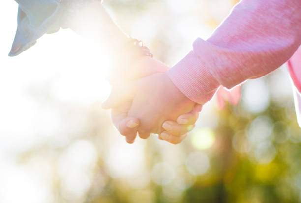 istock Parent and child holding hands closeup 1392421675