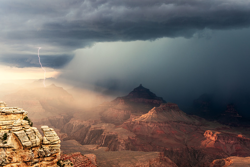A dramatic thunderstorm with rain and lightning over the Grand Canyon at sunset in Grand Canyon National Park, Arizona, USA.