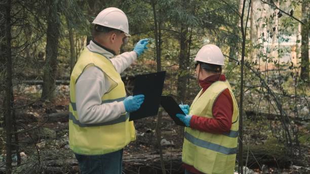 istock Man, woman environmentalists document offense - forest pollution and issue fine 1392428971