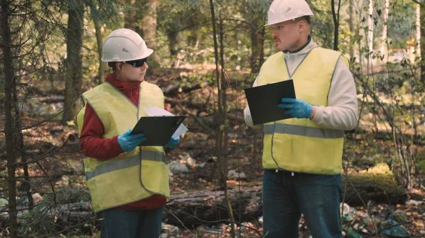 istock Man, woman environmentalists document offense - forest pollution and issue fine 1392428975