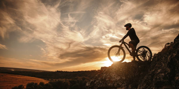 Man on mountain bike against sundown sky stock photo
