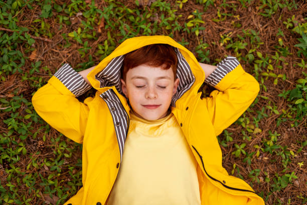 istock Carefree redhead boy in yellow raincoat on grass 1392429112