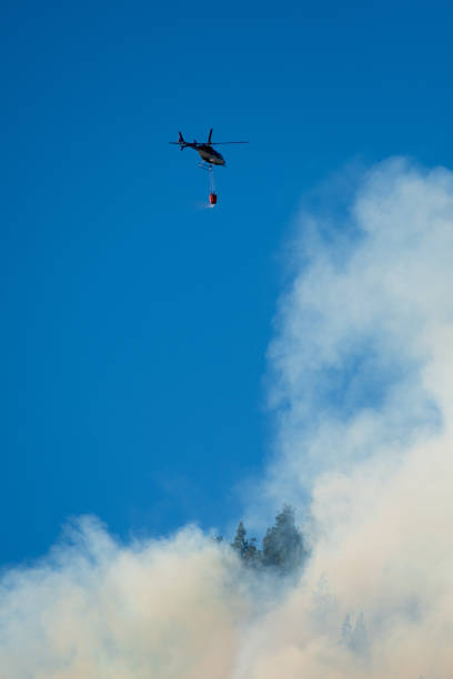 istock Helicopter with bag of water fighting a large forest fire. 1392440679