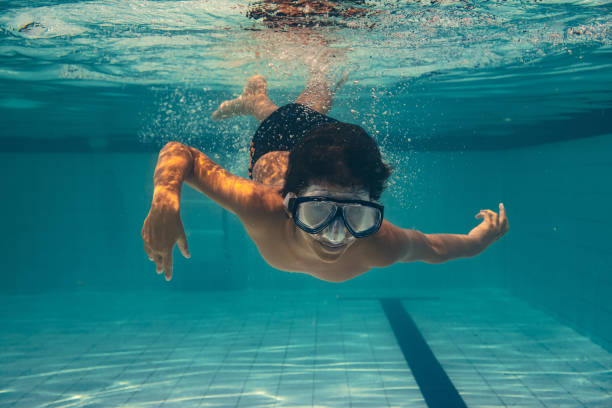 istock Boy diving into the pool with diving goggles 1392441387