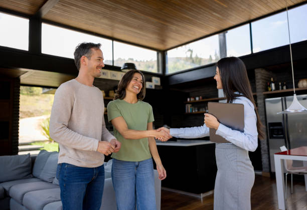 Real estate agent handshaking with a couple of customers Happy real estate agent handshaking with a couple of customers interested in buying a house - home ownership concepts estate agent stock pictures, royalty-free photos & images