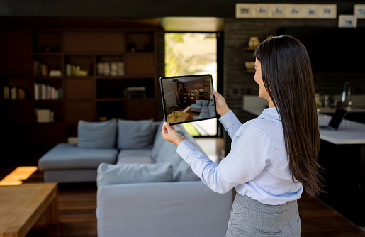 Happy Latin American real estate agent making a virtual showing of a house for sale using a tablet