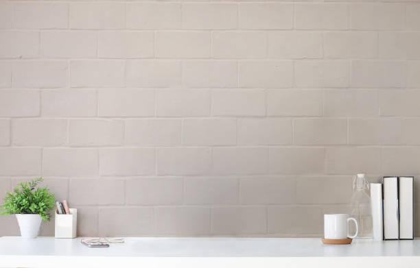 istock Comfortable workplace with houseplant, coffee cup, books and pencil holder on white table. 1392446533
