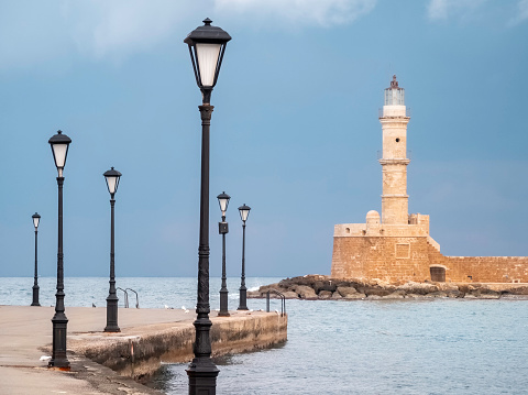 Lamp posts on the  harbour in Chania with the old lighthouse in the background.