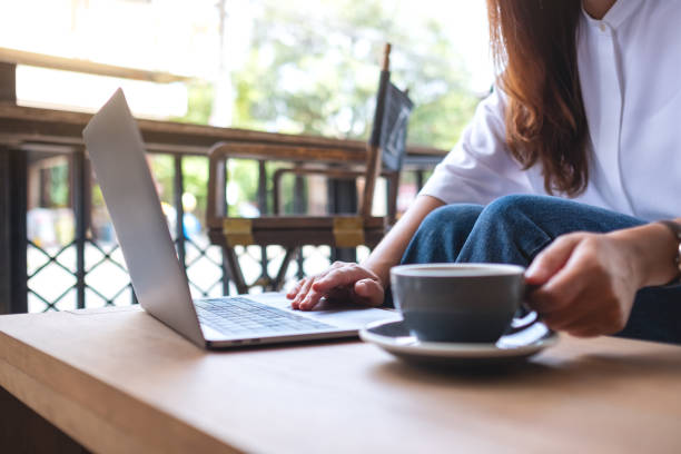 istock Closeup image of a woman working and typing on laptop computer while drinking coffee 1392448316