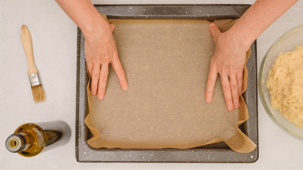 Placing parchment paper onto baking pan. Step by step homemade pizza recipe, baking process, view from above