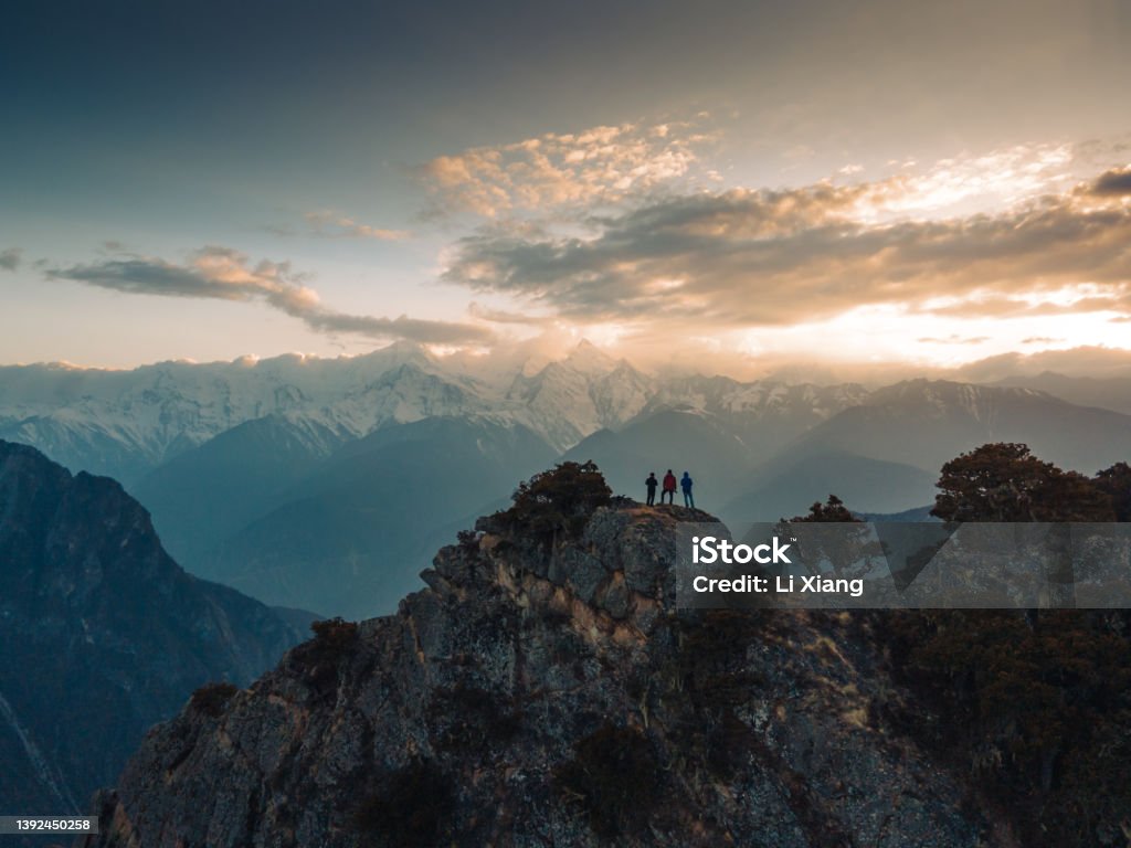 A small group of people in front of a snow-capped mountain A small crowd watched from the top of the snow-capped mountain Mountain Climbing Stock Photo