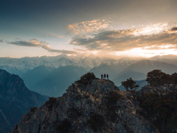 um pequeno grupo de pessoas em frente a uma montanha coberta de neve - sunrise asia china climbing - fotografias e filmes do acervo