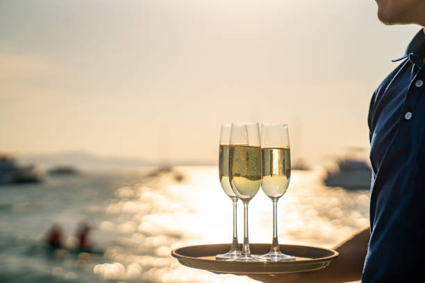 hombre camarero sosteniendo una copa de champán en la bandeja para servir al pasajero en el barco catamarán - yacht fotografías e imágenes de stock
