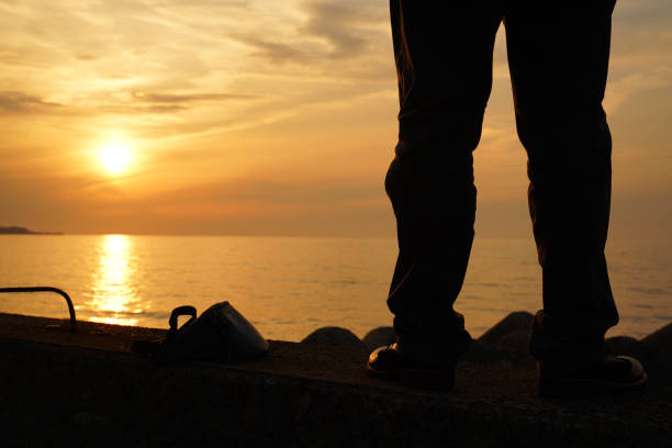 A man standing on a breakwater and looking at the sea