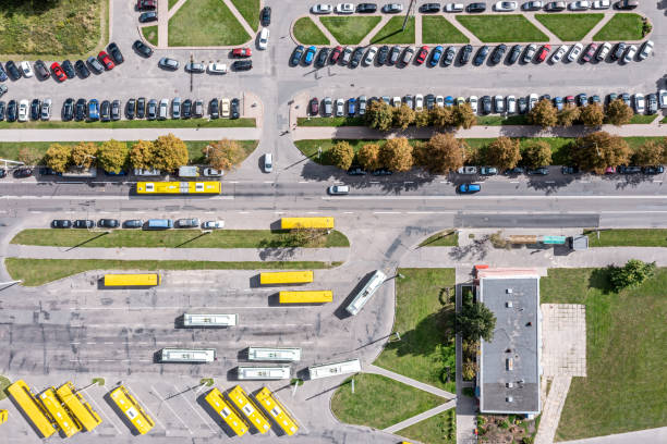 vue aérienne du dépôt de bus avec bus jaunes et du parking avec voitures garées. paysage urbain par temps ensoleillé. - traffic car street parking photos et images de collection