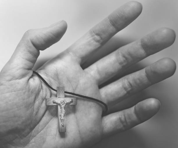 metal figure of the crucified jesus christ on a wooden cross in a motionless hand. - praying human hand worshipper wood imagens e fotografias de stock