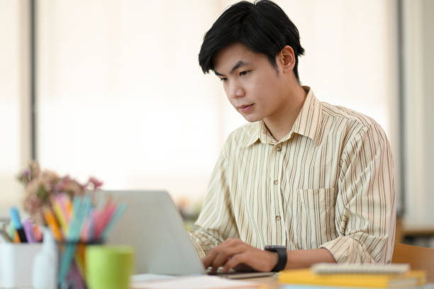 istock Handsome Asian young businessman working his project on laptop 1392459564