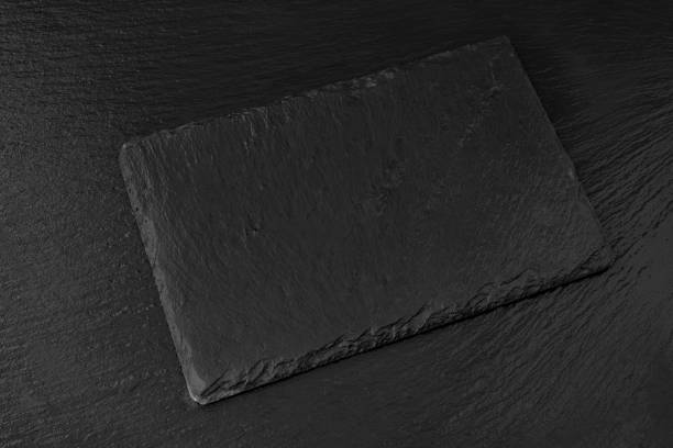 istock Black slate board or plate on dark stone texture background top view. Empty space for food, sushi, text, menu 1392461060