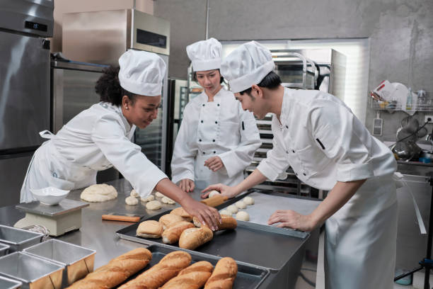 istock Chefs team in uniforms prepare to bake bread and pastry in stainless kitchen. 1392461693