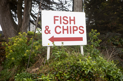 Sign on a roadside verge pointing to a take-away food outlet