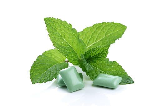 Chewing gum pieces and mint leaves on white background