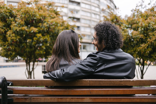 Rear view of a mixed raced couple sitting on a bench