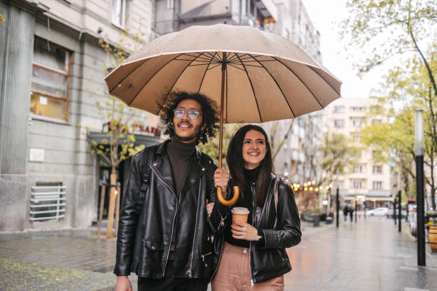 istock Mixed race couple standing under umbrella 1392470253