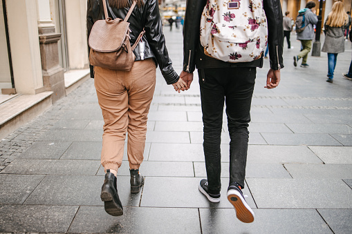 Rear view of a mixed race urban couple walking down the street and holding hands