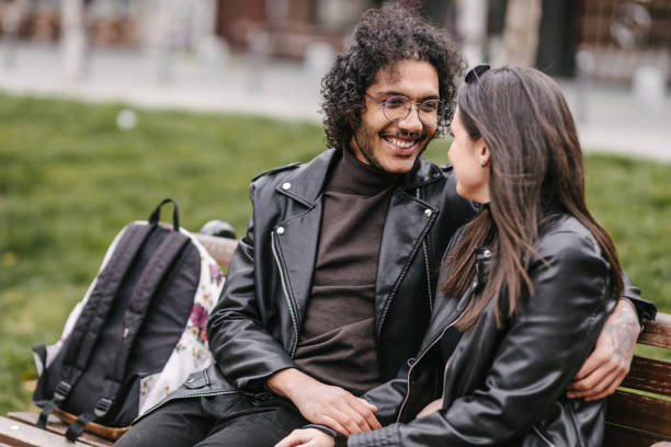 istock Mixed raced couple sitting on a bench 1392470355